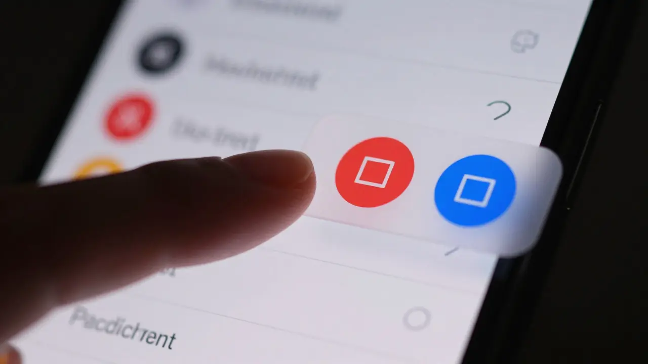 Finger swiping on a phone screen to reveal hidden contextual action buttons
